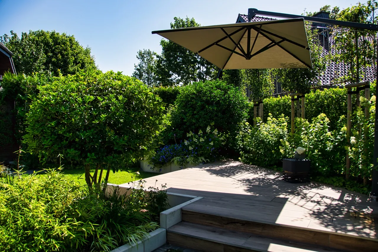 Üppig bepflanzter Privatgarten mit Holzterrasse und schattigem Sitzplatz in Straelen
